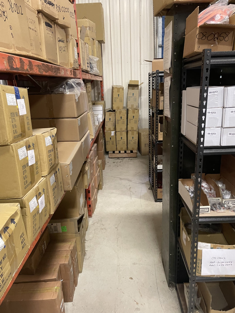 Boxed motorcycle parts on storage racks and pallets in the PartsNMore warehouse