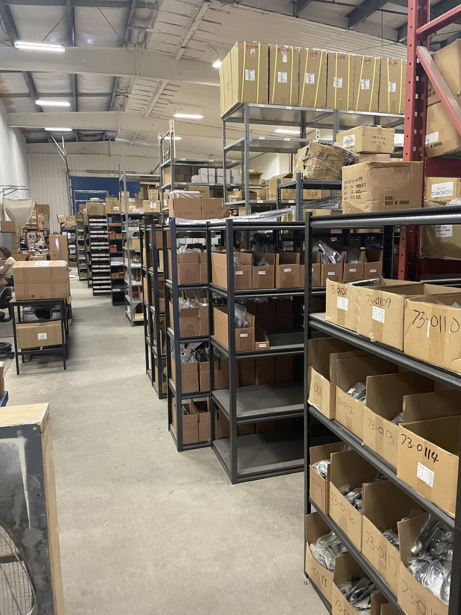 Rows of shelving, numbered parts bins and cartons in the PartsNMore warehouse